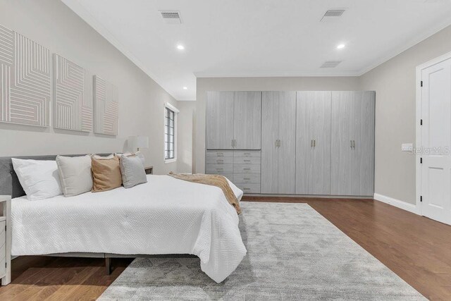 bedroom featuring visible vents, ornamental molding, wood finished floors, recessed lighting, and baseboards