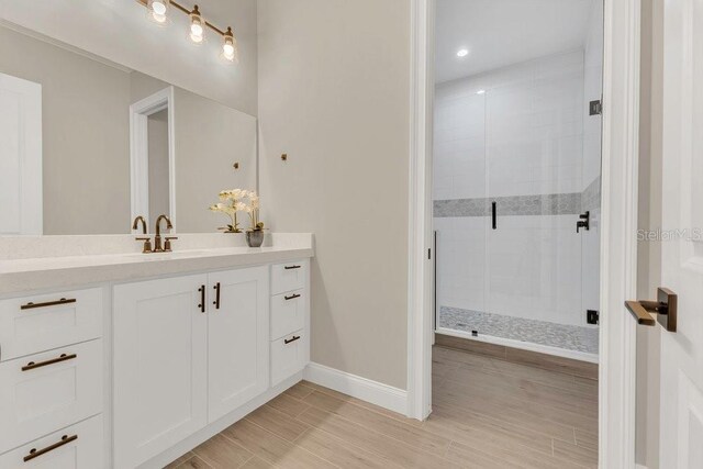 bathroom with vanity, a shower stall, baseboards, and wood finish floors