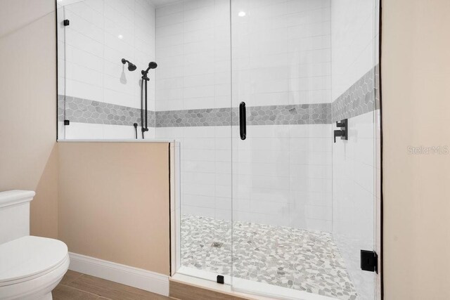 bathroom featuring baseboards, toilet, and a stall shower