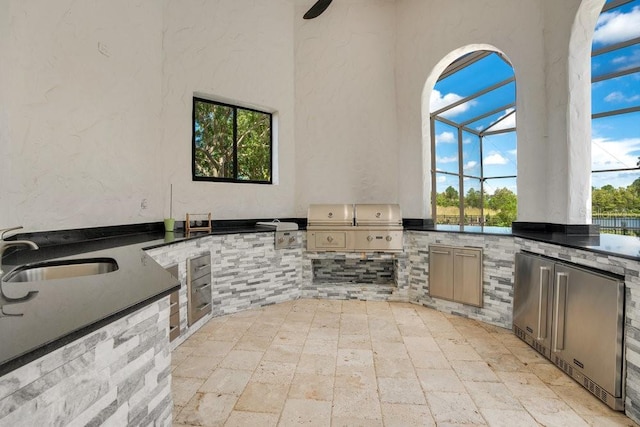 view of patio featuring a sink, glass enclosure, and exterior kitchen