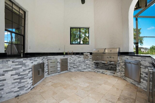 view of patio featuring a sink, area for grilling, a lanai, and exterior kitchen