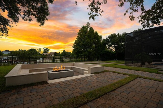 patio terrace at dusk with glass enclosure, fence, and an outdoor fire pit