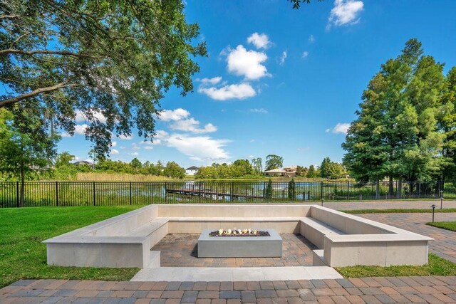 view of patio featuring fence, a water view, and an outdoor fire pit