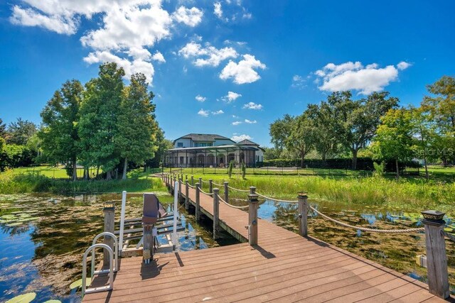 view of dock with glass enclosure and a water view