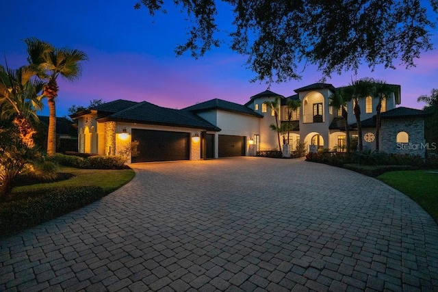 mediterranean / spanish home featuring stucco siding, decorative driveway, and a garage