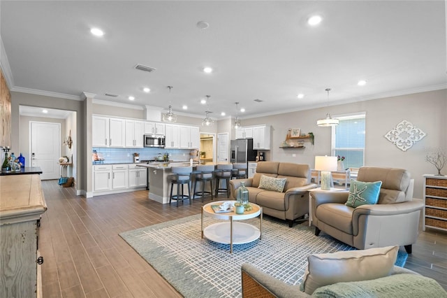 living room featuring recessed lighting, visible vents, wood finished floors, and crown molding