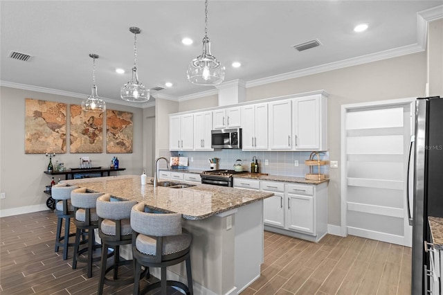 kitchen featuring tasteful backsplash, visible vents, wood finish floors, stainless steel appliances, and a sink