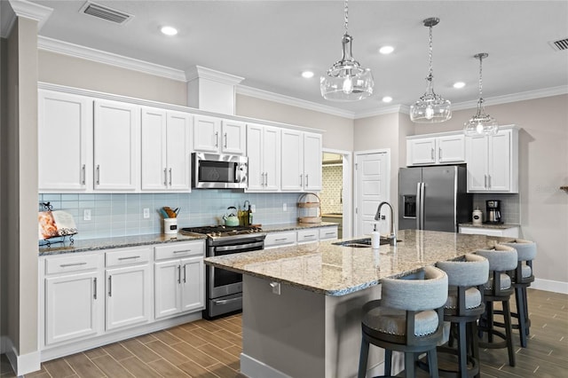 kitchen featuring visible vents, wood finish floors, white cabinets, stainless steel appliances, and a sink