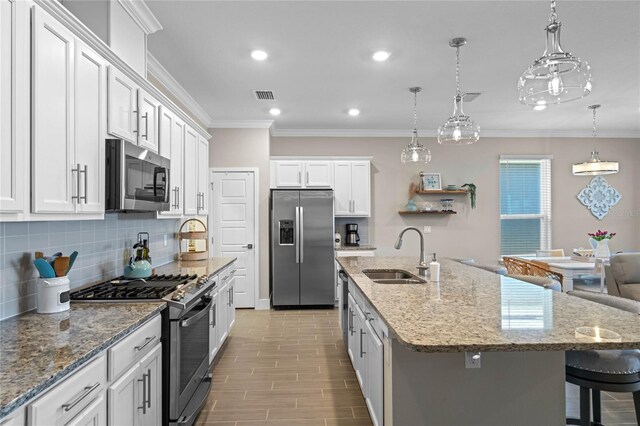 kitchen featuring visible vents, stainless steel appliances, crown molding, and a sink