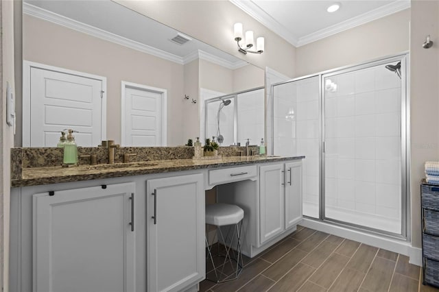 bathroom featuring visible vents, a shower stall, crown molding, and double vanity