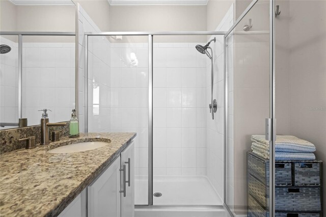 full bathroom featuring a shower stall, vanity, and ornamental molding