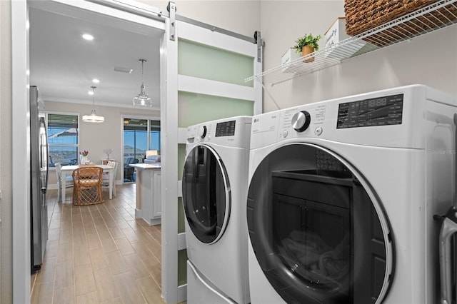 washroom featuring laundry area, washer and dryer, light wood-type flooring, and crown molding