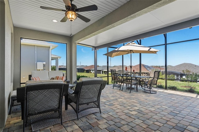 sunroom / solarium with a healthy amount of sunlight, a residential view, and ceiling fan