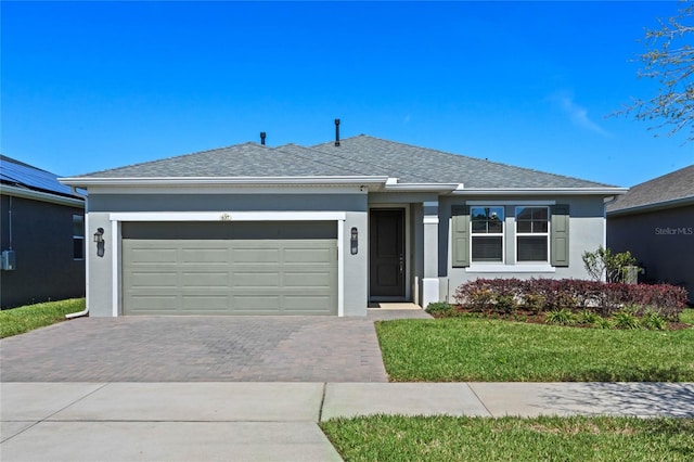 single story home featuring stucco siding, decorative driveway, a garage, and a front lawn