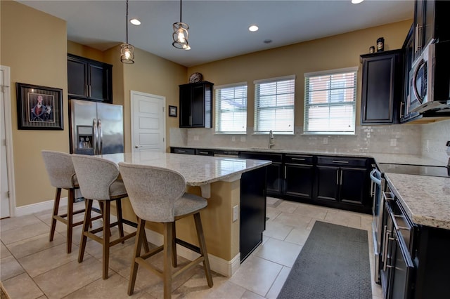 kitchen featuring appliances with stainless steel finishes, a sink, dark cabinets, and a kitchen island