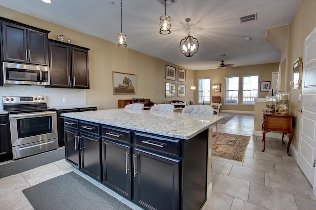 kitchen featuring tasteful backsplash, visible vents, appliances with stainless steel finishes, open floor plan, and pendant lighting