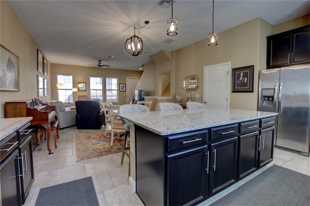 kitchen with visible vents, stainless steel fridge with ice dispenser, a kitchen island, decorative light fixtures, and light tile patterned flooring