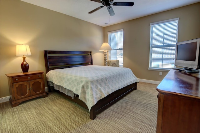 bedroom featuring ceiling fan, multiple windows, baseboards, and light colored carpet