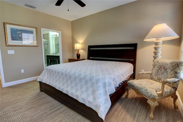 bedroom with ceiling fan, ensuite bathroom, light colored carpet, visible vents, and baseboards