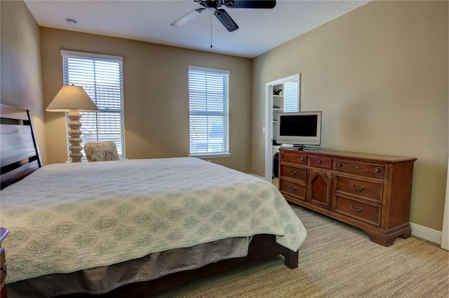 bedroom featuring a ceiling fan, light colored carpet, baseboards, and multiple windows