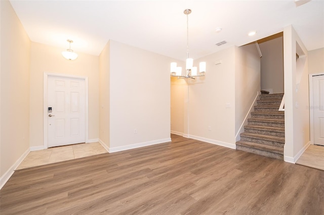 foyer featuring a chandelier, stairway, light wood-type flooring, and baseboards