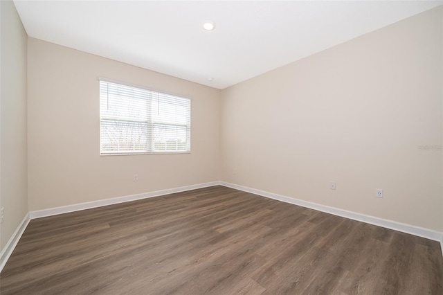 unfurnished room with dark wood-type flooring and baseboards