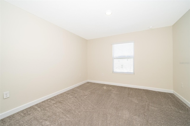 carpeted spare room featuring baseboards