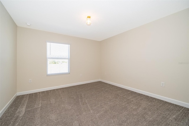 empty room featuring carpet and baseboards