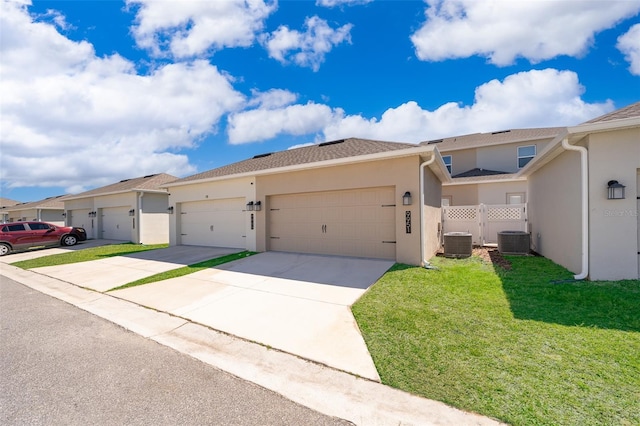 view of front of home with central AC unit, concrete driveway, fence, a front lawn, and stucco siding