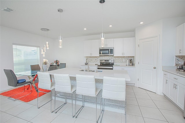 kitchen featuring tasteful backsplash, light countertops, appliances with stainless steel finishes, white cabinets, and a sink