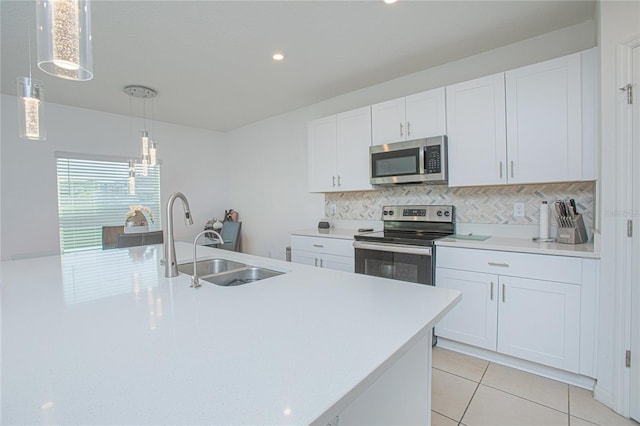 kitchen with decorative backsplash, appliances with stainless steel finishes, light tile patterned flooring, white cabinetry, and a sink