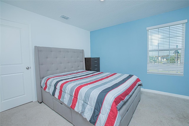 bedroom featuring baseboards, visible vents, carpet floors, and a textured ceiling