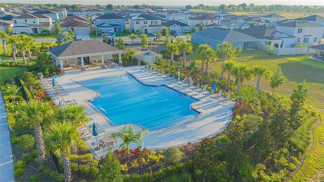 community pool with a patio area, fence, and a residential view