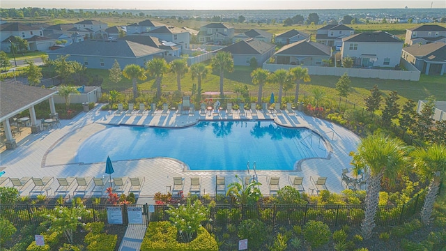 pool with a patio area, fence, and a residential view