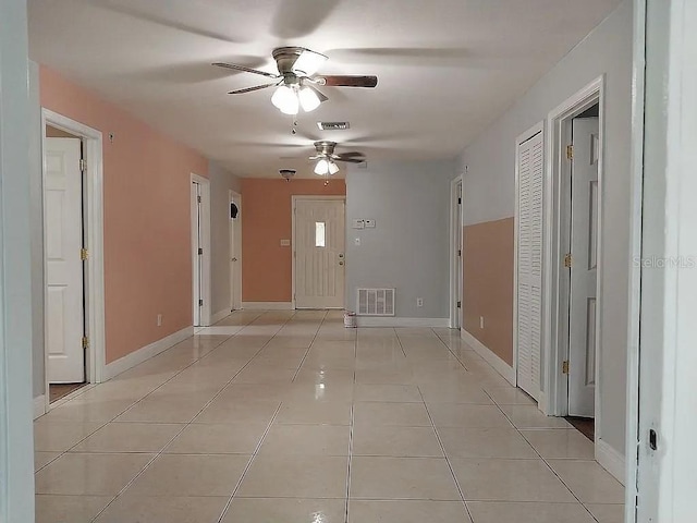 hallway featuring light tile patterned floors, visible vents, and baseboards