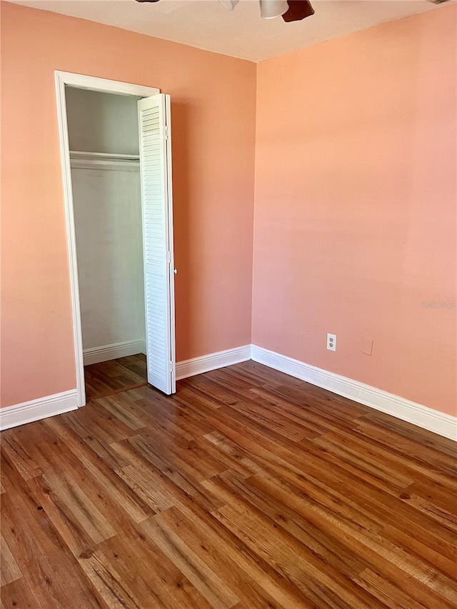 unfurnished bedroom with ceiling fan, a closet, baseboards, and dark wood finished floors