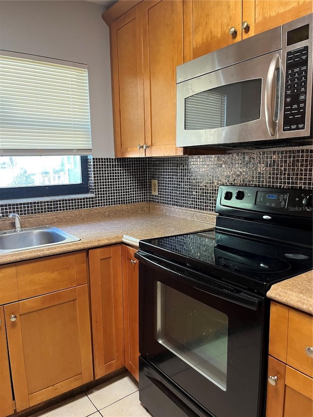 kitchen featuring tasteful backsplash, stainless steel microwave, black range with electric stovetop, and a sink