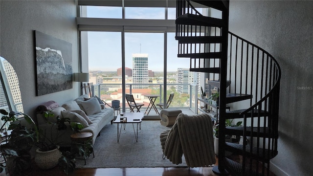 living area with a view of city, wood finished floors, stairs, and a textured wall