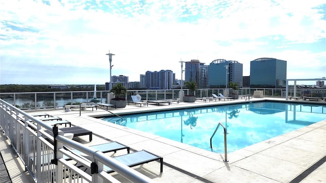 pool with a patio area, a city view, and fence