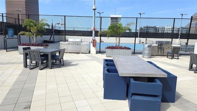 view of patio / terrace with community basketball court, outdoor dining area, fence, and grilling area