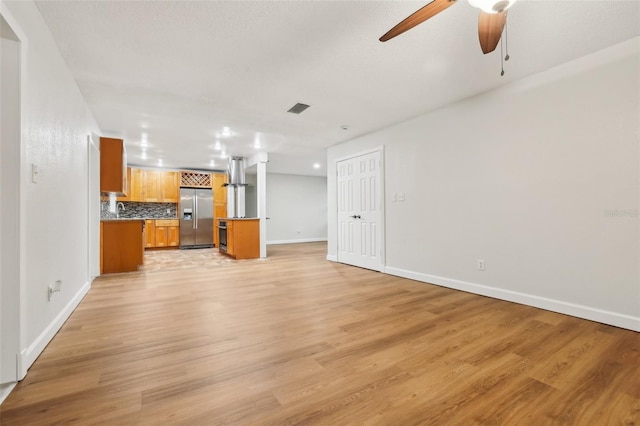 unfurnished living room with baseboards, visible vents, ceiling fan, and light wood finished floors