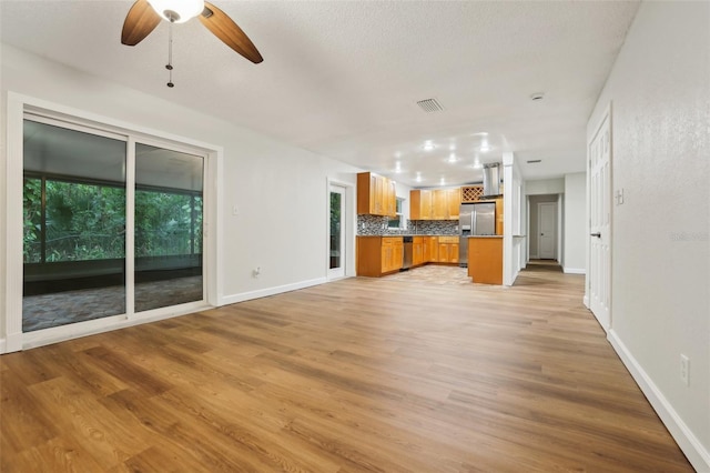 unfurnished living room with visible vents, a ceiling fan, light wood-style flooring, and baseboards