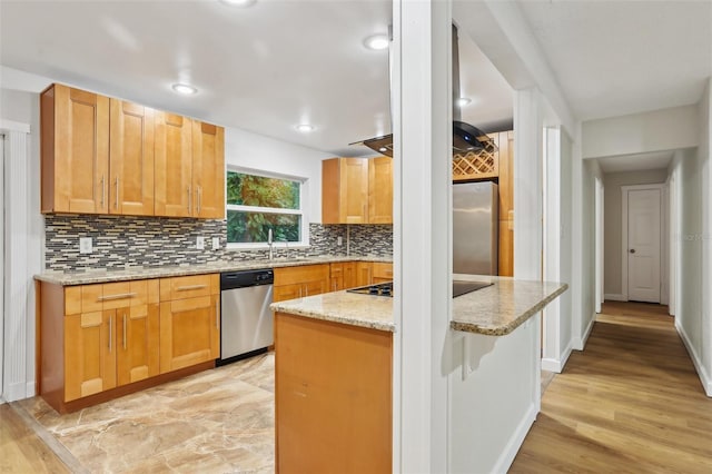 kitchen with a kitchen island, appliances with stainless steel finishes, backsplash, light stone countertops, and a sink