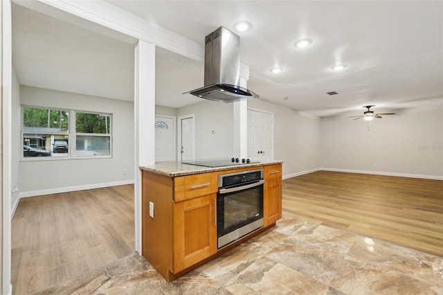 kitchen featuring island range hood, stainless steel oven, black electric cooktop, and baseboards