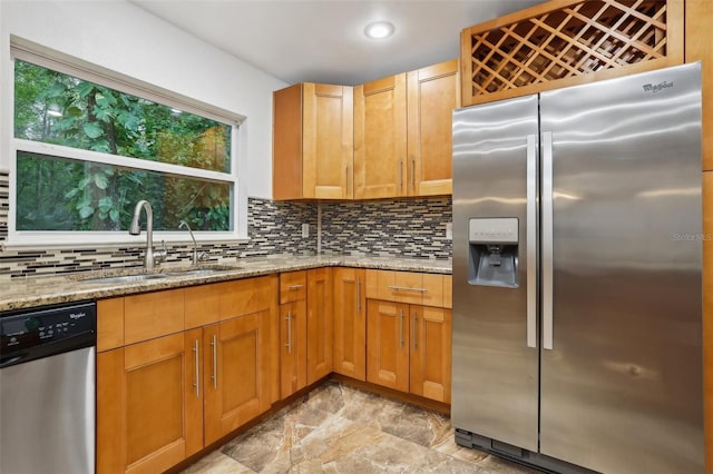 kitchen featuring appliances with stainless steel finishes, a sink, light stone countertops, backsplash, and recessed lighting