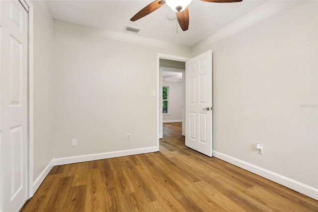 unfurnished bedroom featuring light wood finished floors, baseboards, visible vents, ceiling fan, and a closet