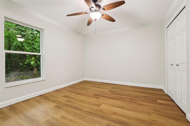 unfurnished bedroom featuring light wood-type flooring, a closet, ceiling fan, and baseboards