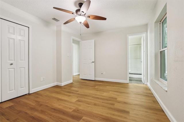 unfurnished bedroom with light wood-style flooring, visible vents, baseboards, and ensuite bathroom