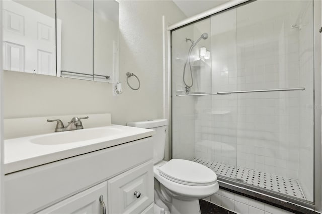 bathroom featuring toilet, a stall shower, and vanity