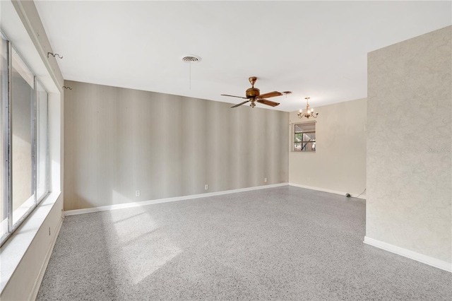 unfurnished room featuring ceiling fan with notable chandelier, speckled floor, visible vents, and baseboards